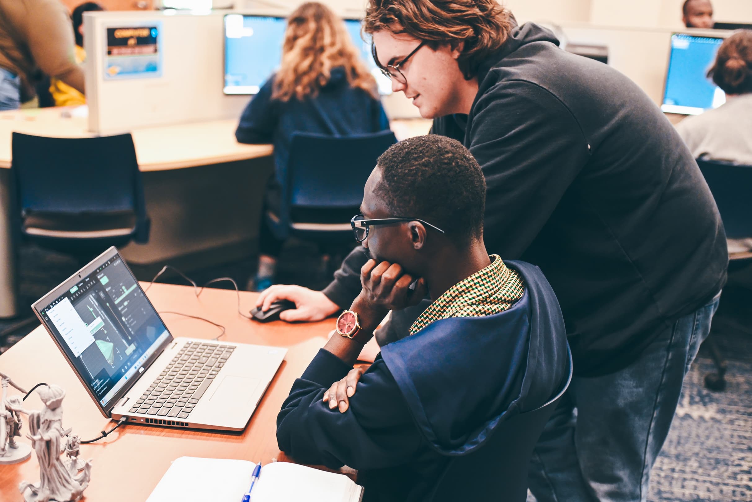 Two students collaborating on a 3D modeling project in a computer lab