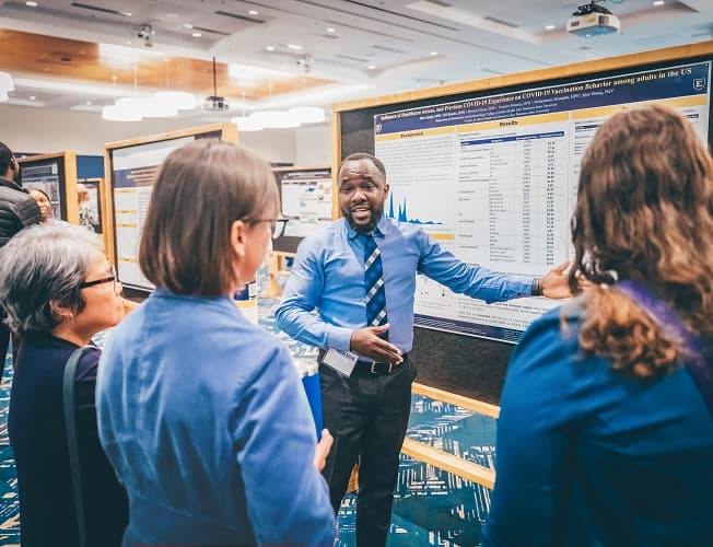 Researcher presenting a healthcare data poster at an academic conference